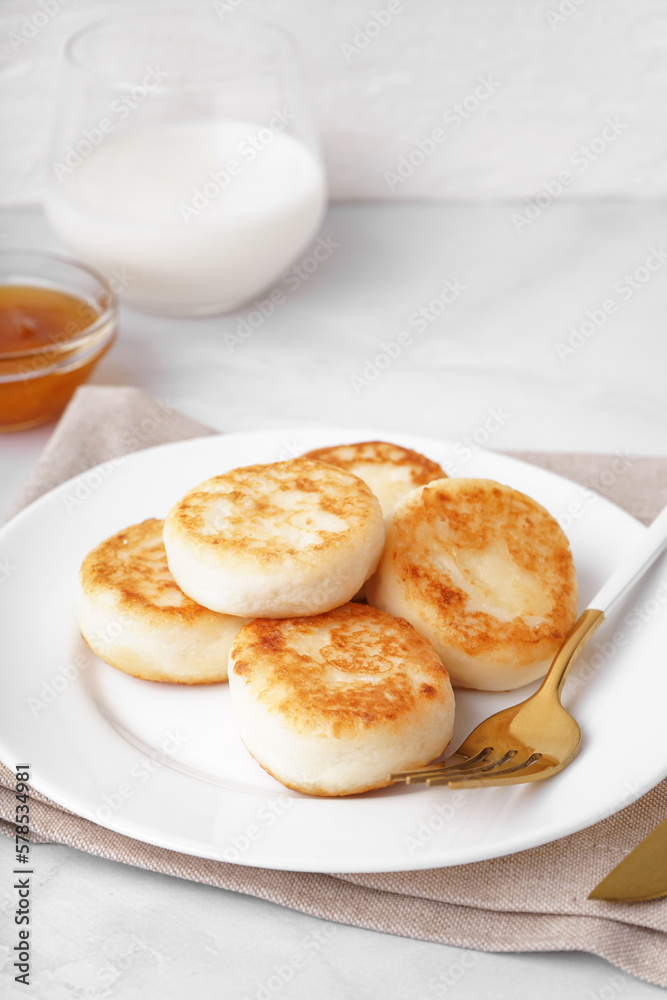 Plate with tasty cottage cheese pancakes on light background, closeup