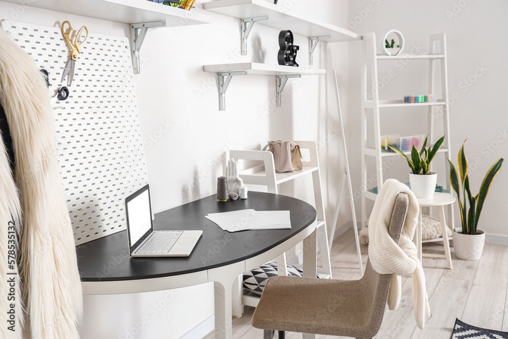 Interior of modern atelier with tailors workplace, shelving units and mirror