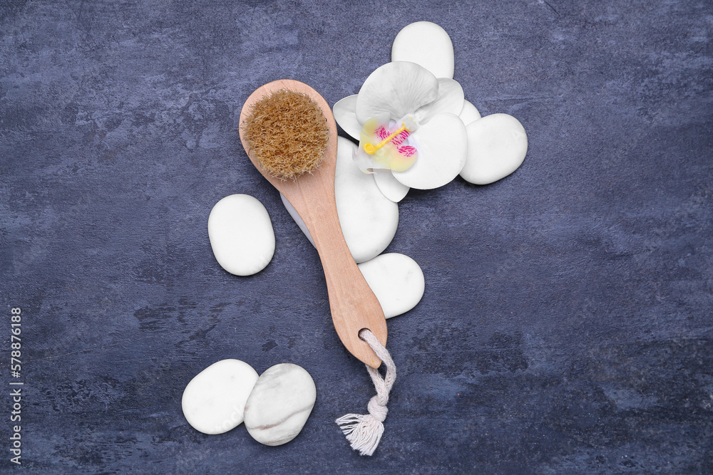 Massage brush, spa stones and flower on dark background