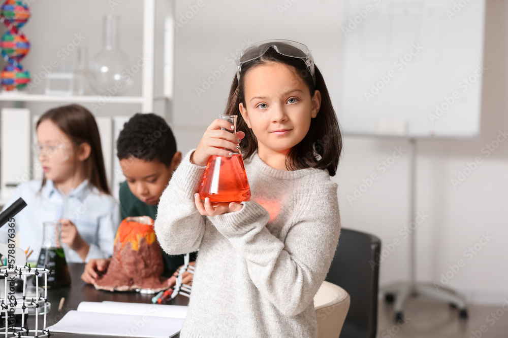 Little girl with safety goggles and conical flask in science classroom