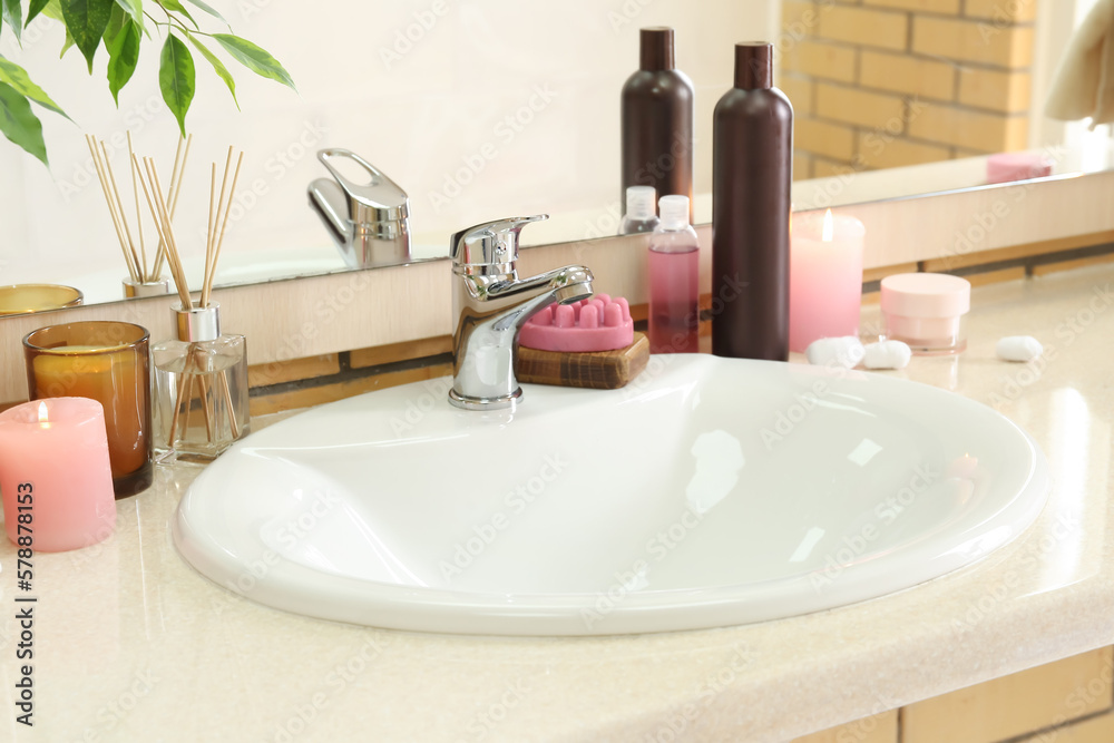 Table with ceramic sink, burning candles and bath supplies