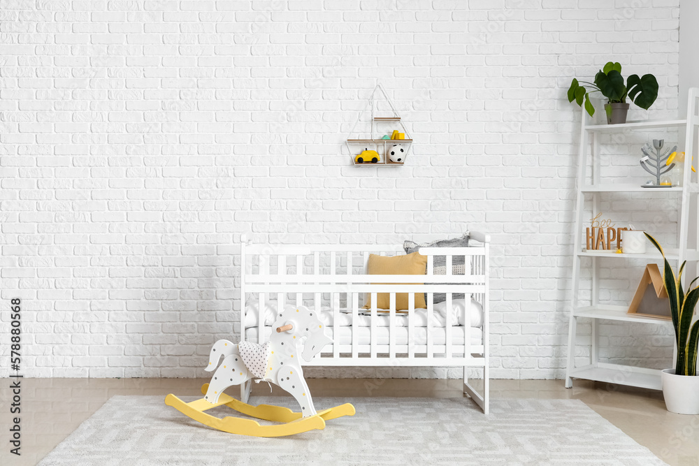 Interior of childrens bedroom with crib, rocking horse and shelving unit