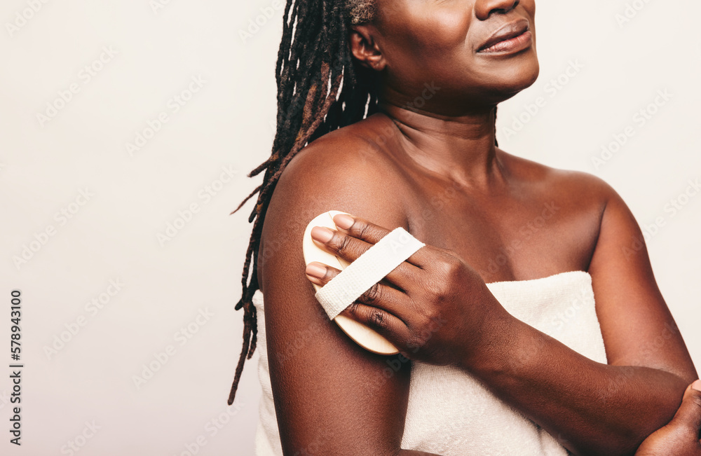 Mature woman exfoliating her skin with a brush