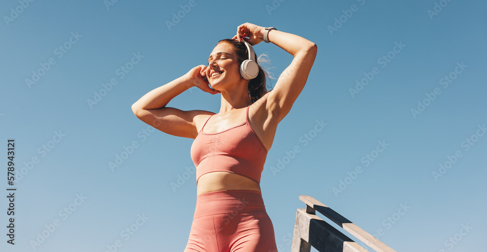 Caucasian sports woman listening to music on headphones outdoors