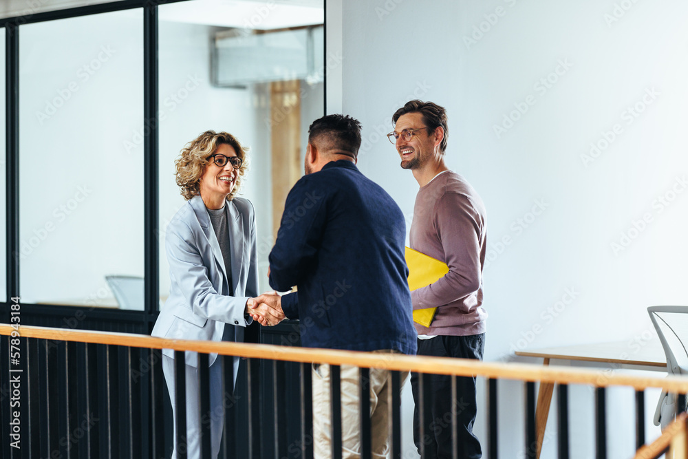 Successful business woman shaking hands with a client in an office