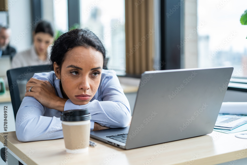 Exhausted Latino young businesswoman overworking in office workplace. 