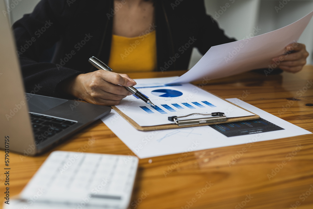 Businesswoman working with financial documents analyzing market growth report and company sales.