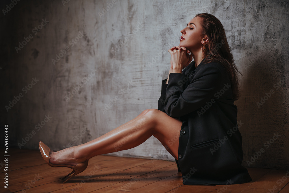 Young business style woman sitting on gray wall background