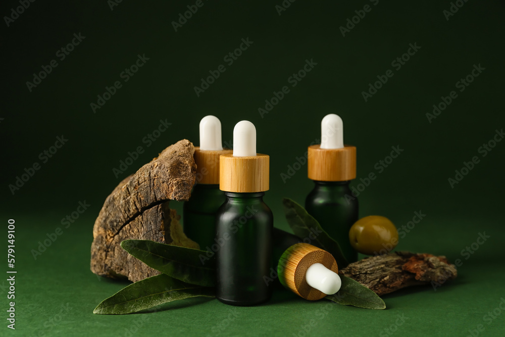 Bottles of olive essential oil on green background