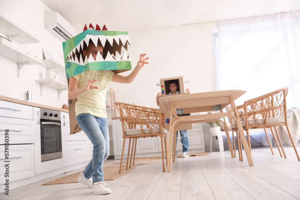 Little girl in cardboard dinosaur costume playing at home