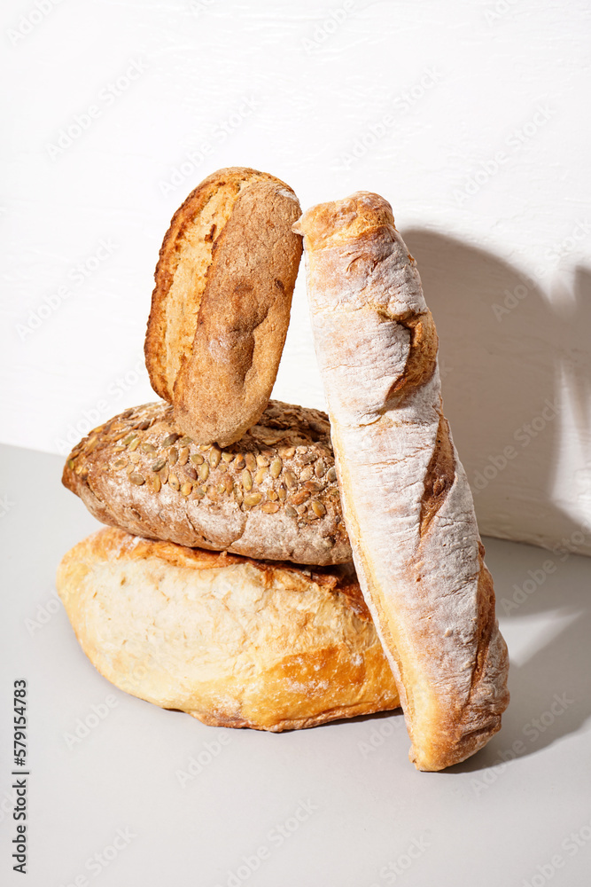 Loaves of different bread on table white wall