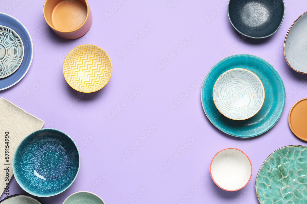 Composition with clean ceramic plates and bowls on lilac background