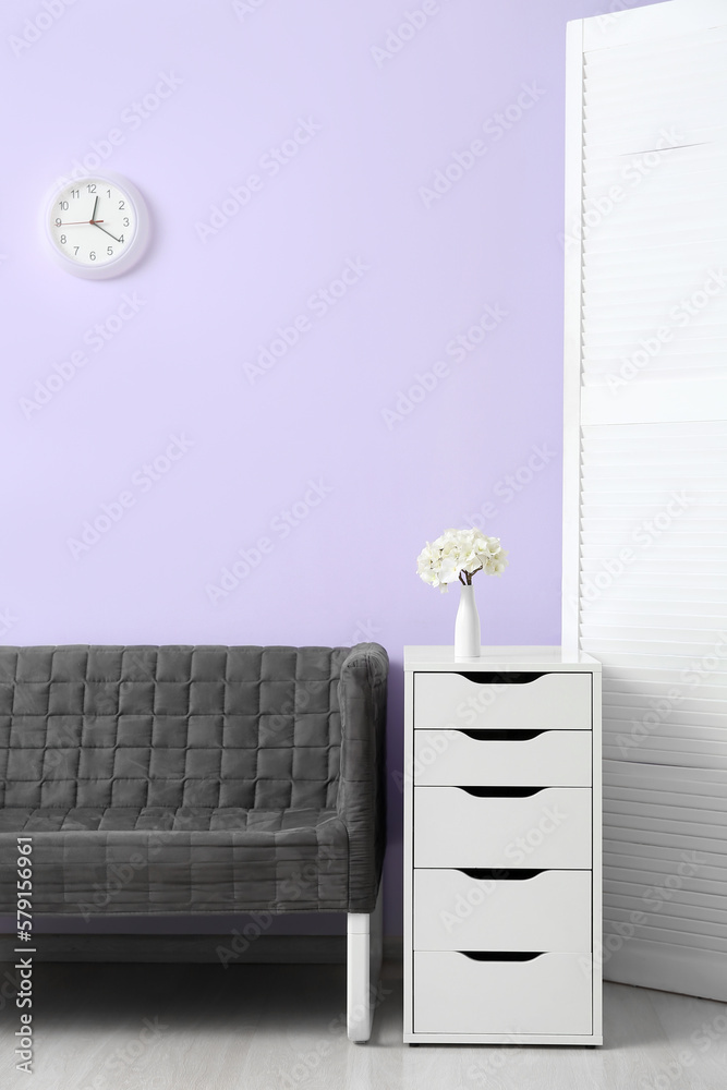 Interior of living room with stylish grey sofa near lilac wall