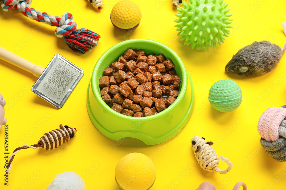 Composition with different pet care accessories and wet food on yellow background