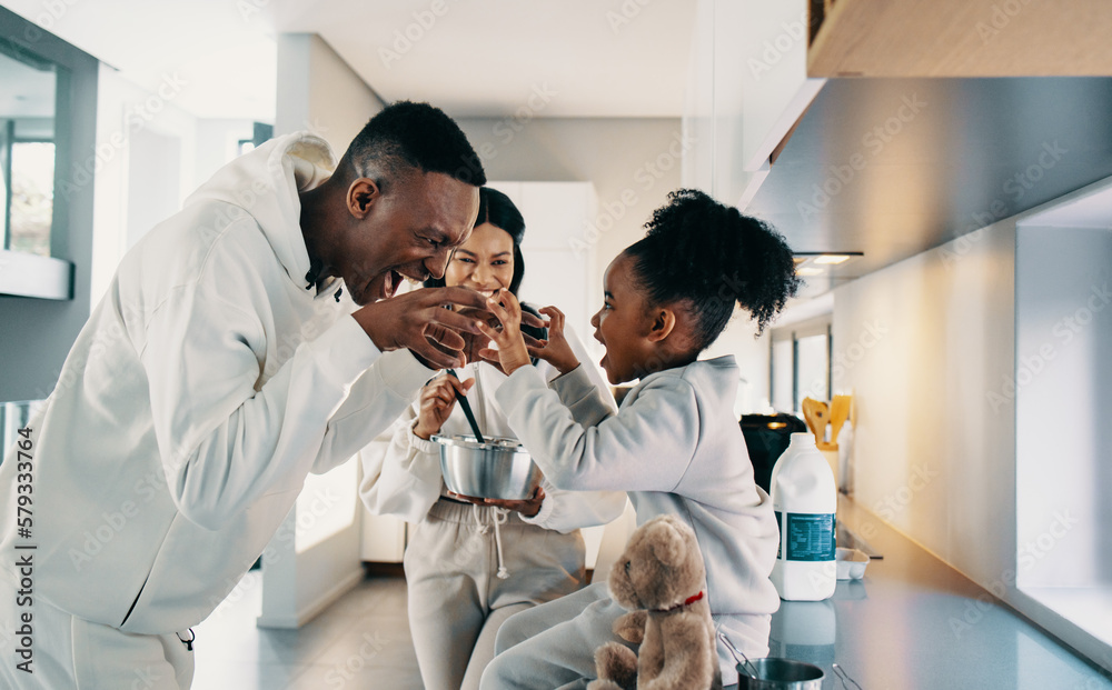 Dad playing with his daughter while mom is cooking in the kitchen