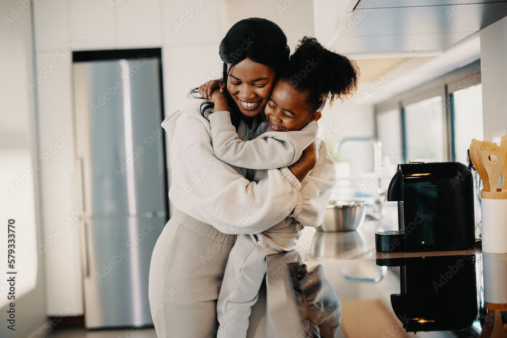 I love you mommy, little girl hugs her mom in the kitchen