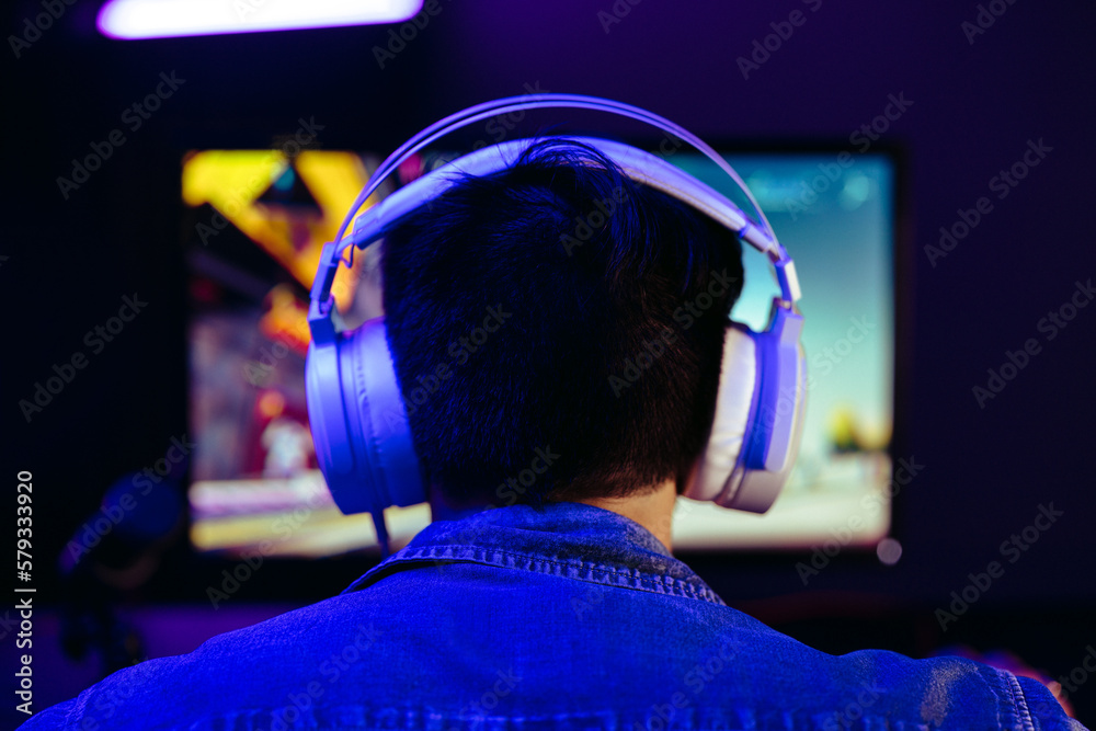 Gamer wearing headphones, live streaming his gameplay for his online subscribers