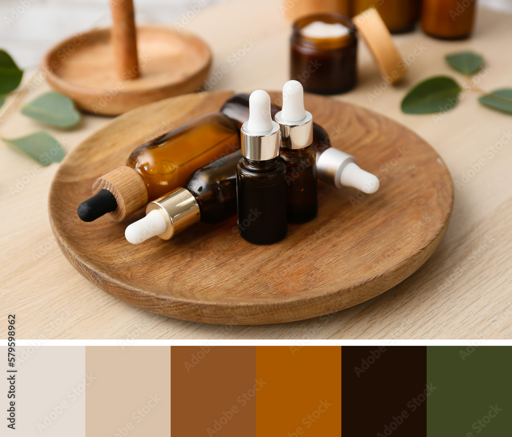 Wooden plate with bottles of essential oil on table. Different color patterns