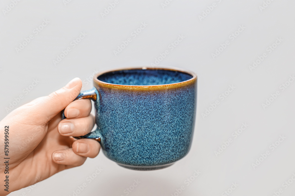 Woman holding blue cup on light background