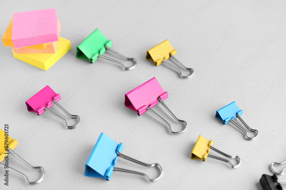 Colorful binder clips and sticky notes on grey background, closeup