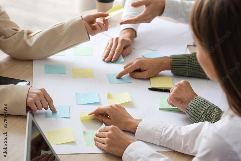 Group of people with sticky notes working on business plan at table in office, closeup