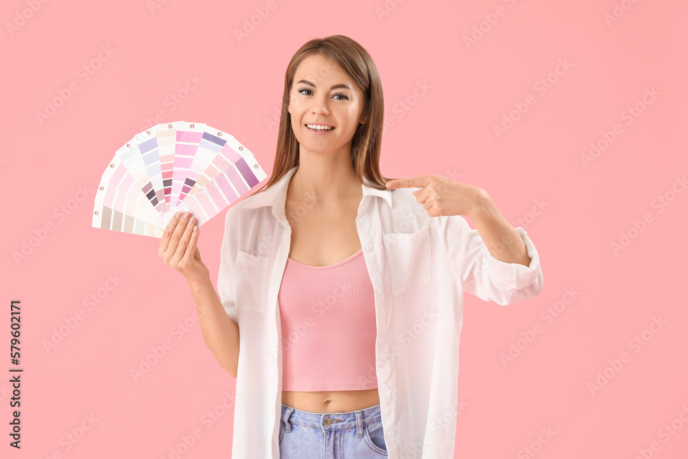 Beautiful woman pointing at paint color palettes on pink background