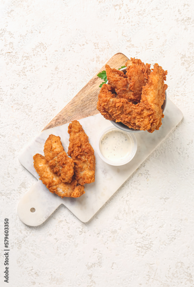 Board with tasty nuggets and sauce on light background