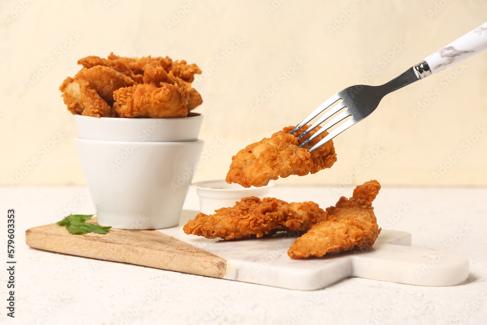 Fork with tasty nuggets on light background