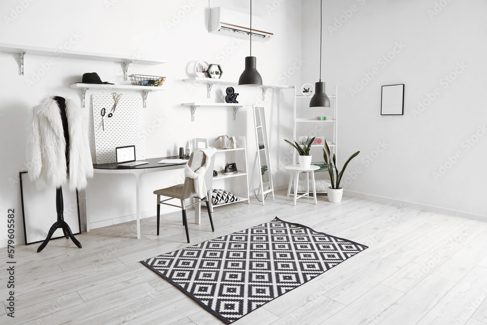 Interior of modern atelier with tailors workplace, shelving units and mirror