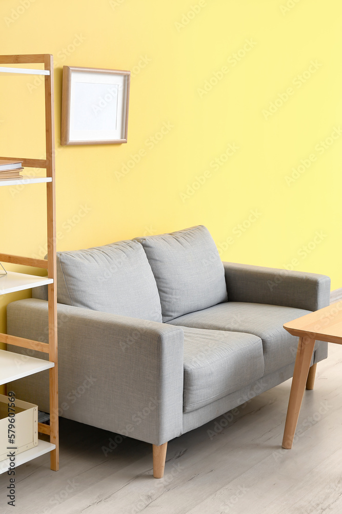 Interior of living room with stylish grey sofa near yellow wall