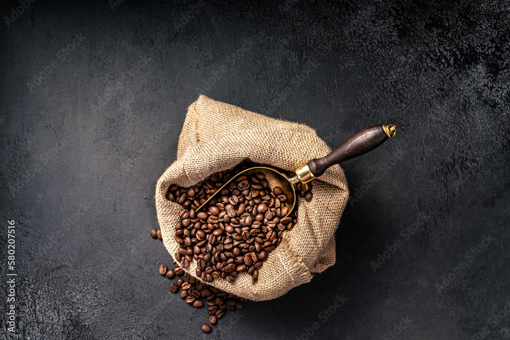 Scoop of coffee beans in a bag on dark background. Top view of coffee. Copy space for text.