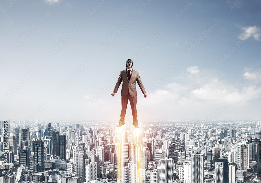 Businessman in suit and aviator hat flying in sky