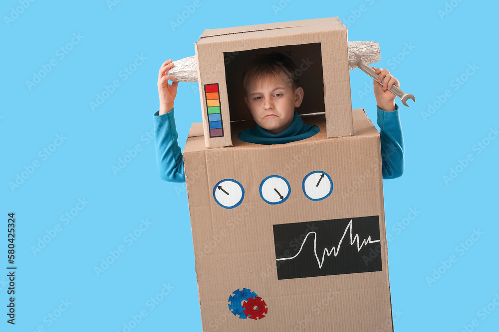 Little boy in cardboard robot costume on blue background