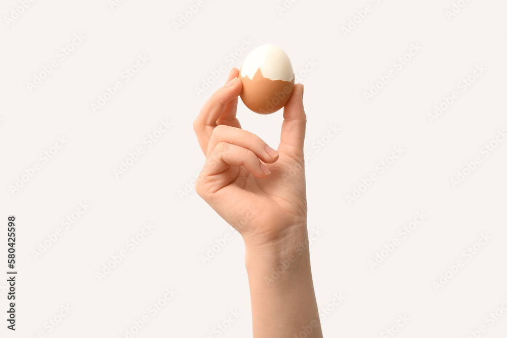 Woman with boiled egg on light background