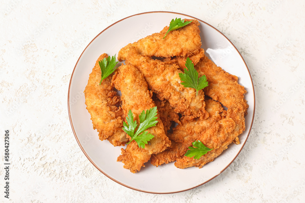 Plate of tasty nuggets with parsley on light background