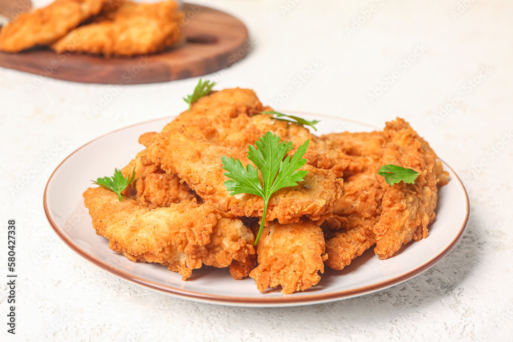 Plate of tasty nuggets with parsley on light background