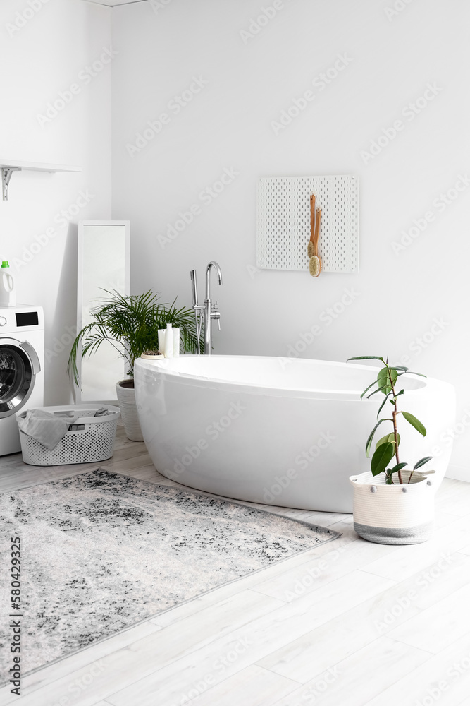 Interior of bathroom with bathtub, houseplants and pegboard