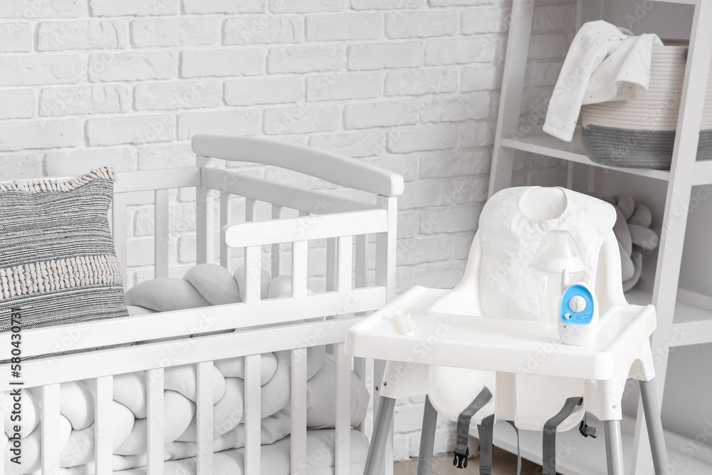 Baby crib and feeding chair in bedroom, closeup