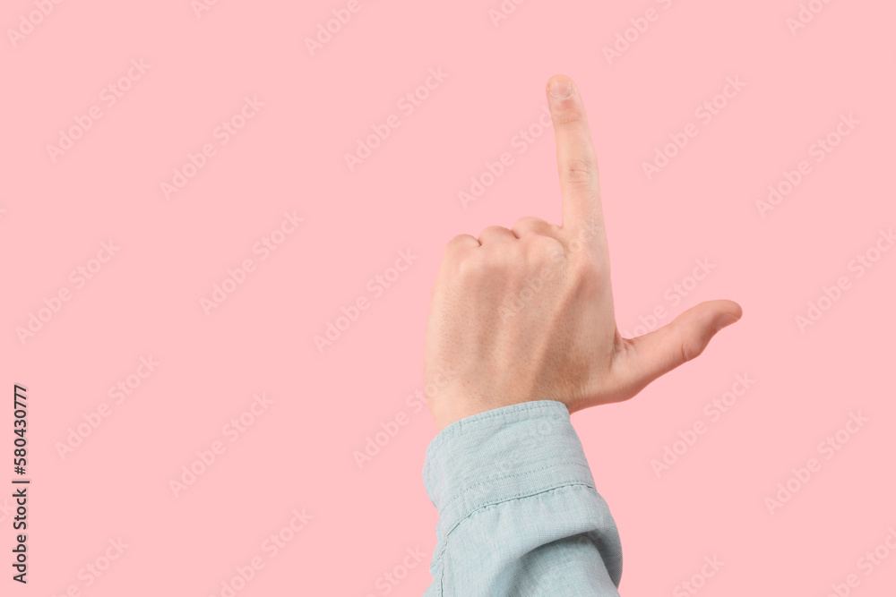 Hand of man showing loser gesture on pink background