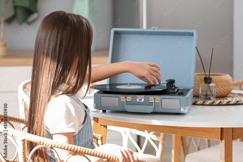 Little girl with record player at table in kitchen