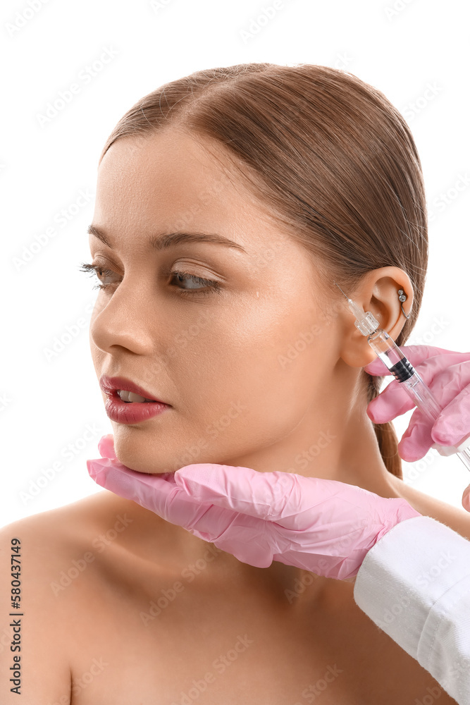 Young woman receiving filler injection in face against white background