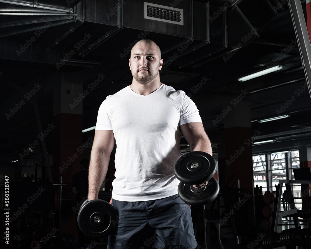 Male bodybuilder engaged with dumbbells in the gym