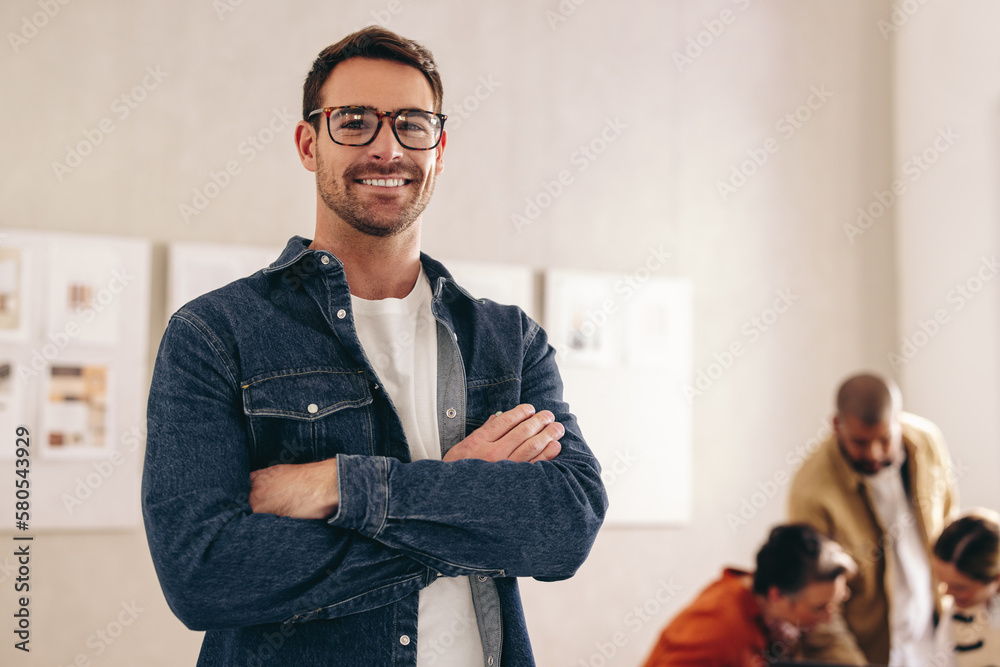 Happy young businessman smiling at the camera with his arms crossed