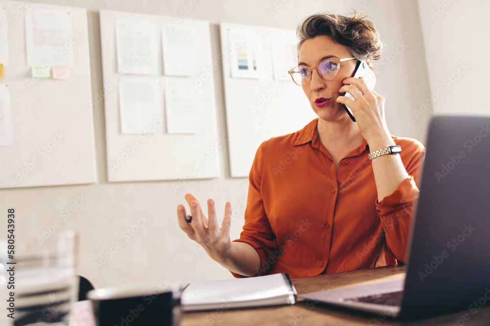 Mature businesswoman speaking on the phone in an office