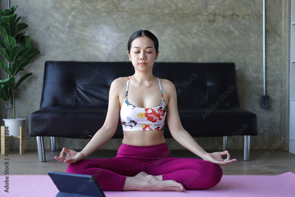 Beautiful asian woman doing relaxing exercise at home and practicing yoga in quiet living room.