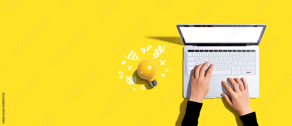 Person using a laptop computer and a light bulb - Flat lay