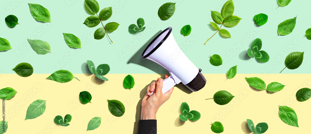 Person holding a megaphone with green leaves - flat lay