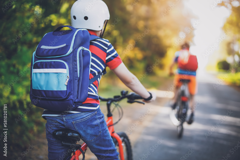 Children riding on bicycles on asphalt road in summer.