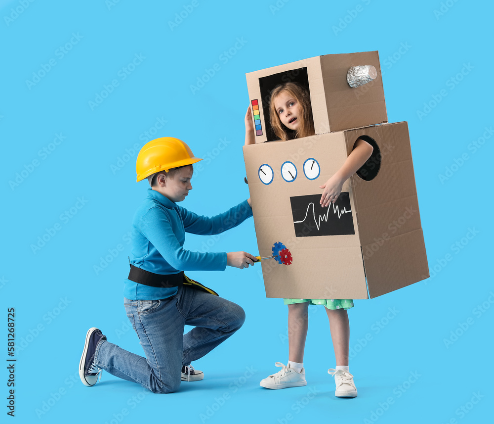 Little boy and girl in cardboard robot costume on blue background