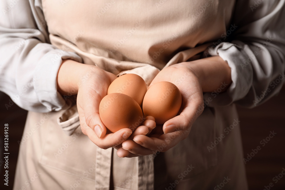 Woman with boiled eggs on dark background, closeup